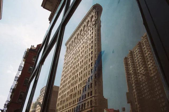 Flatiron Building reflected in glass window, photographic, editorial, muted