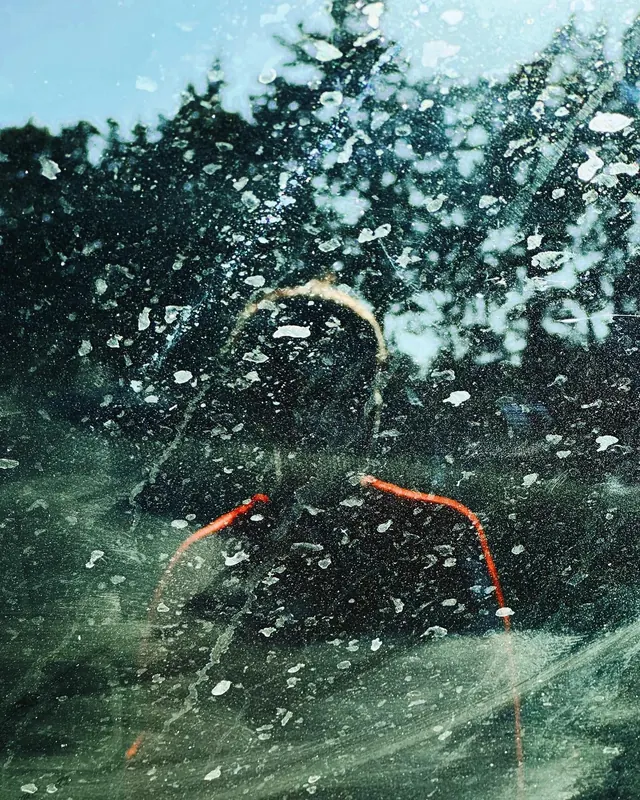 Gritty silhouette through splattered glass, abstract, photographic, dark