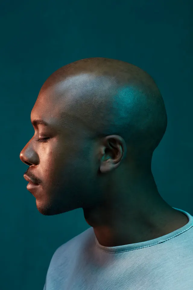 Dual-tone teal and amber profile portrait, editorial, photographic, dark