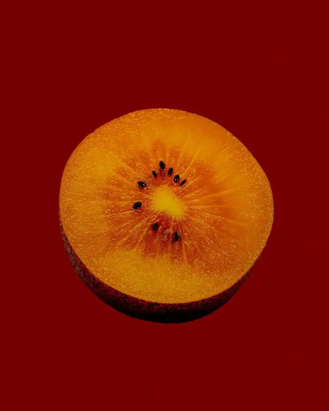 Golden kiwi slice on red, minimal, photographic, vibrant