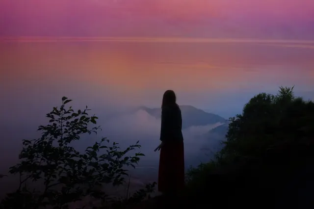Silhouetted figure above misty sunrise valley, photographic, minimal, vibrant
