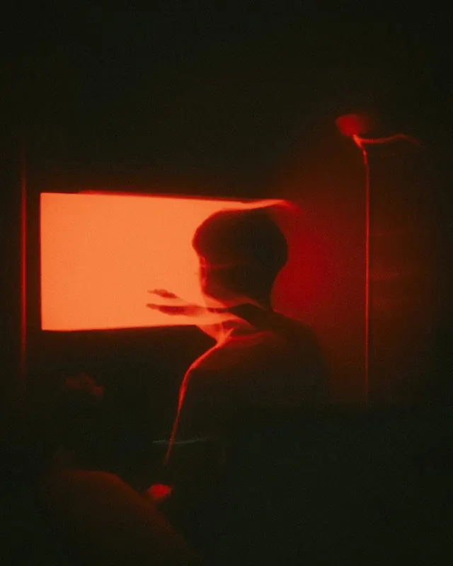 Red long-exposure silhouette before screen glow, photographic, abstract, dark