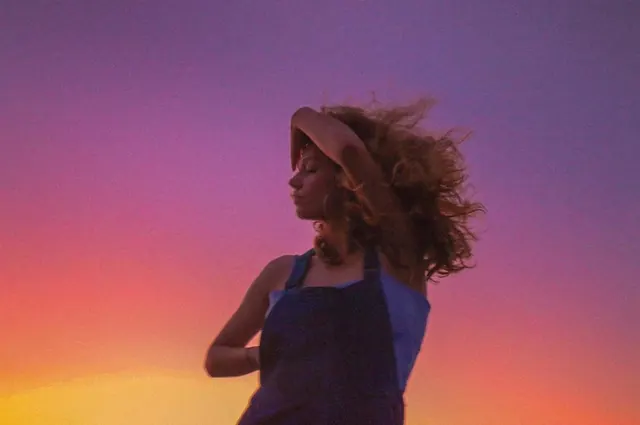 Woman in hat and overalls at sunset, photographic, editorial, vibrant