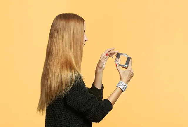 Woman holding smartphone against yellow background