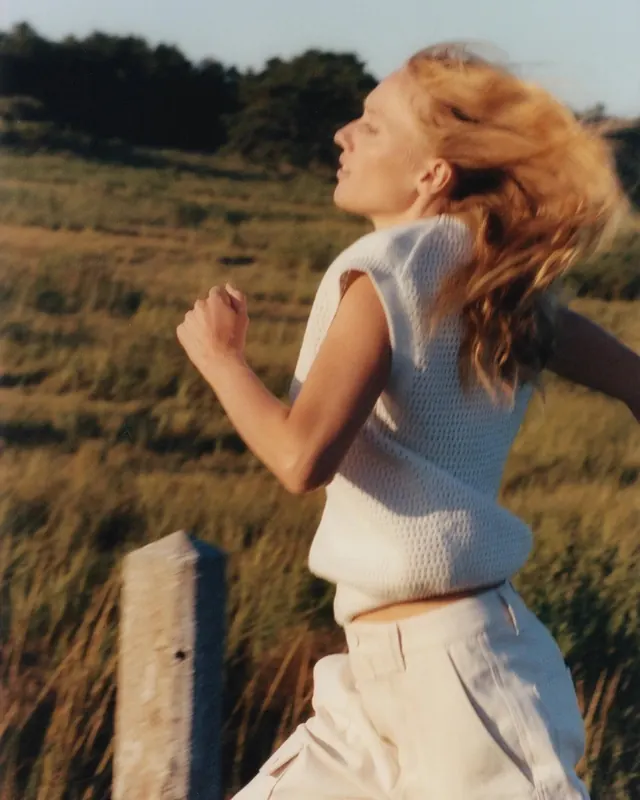 Woman running in golden hour field, photographic, organic, warm
