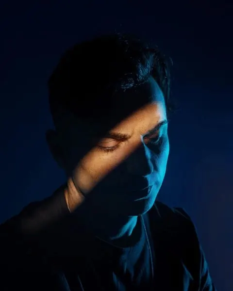 Portrait with dramatic blue side lighting, photographic, minimal, dark
