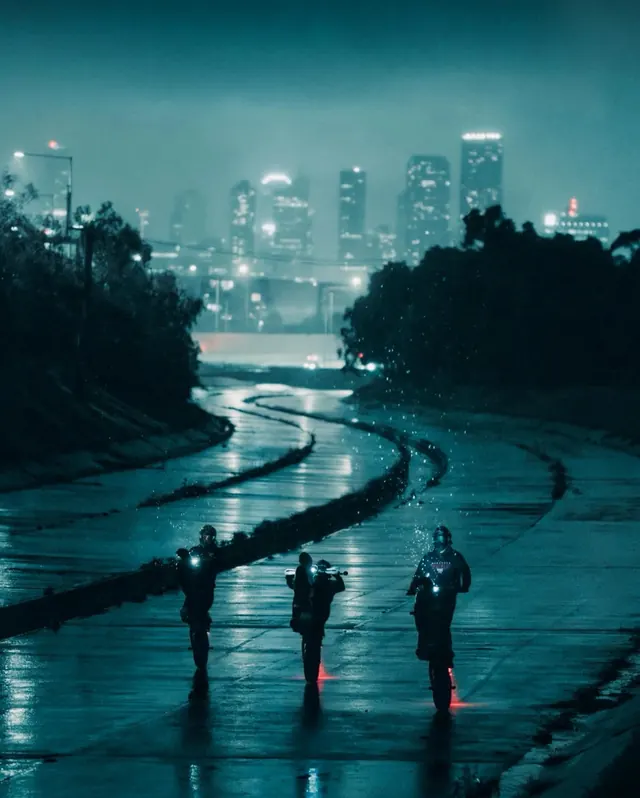 Motorcyclists on wet road at night with city skyline, photographic, dark