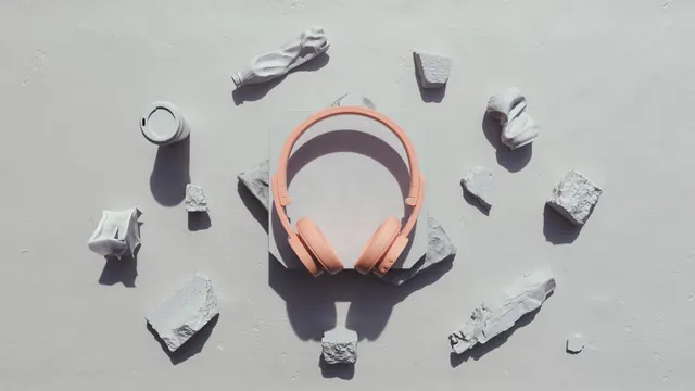 Peach headphones flat lay on stone with debris, minimal, light