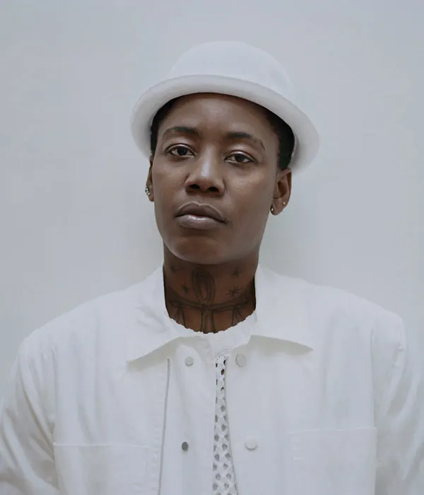 Portrait of man in white bucket hat with neck tattoos, minimal, photographic, light