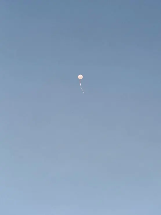 Single balloon in blue sky, minimal, photographic, light