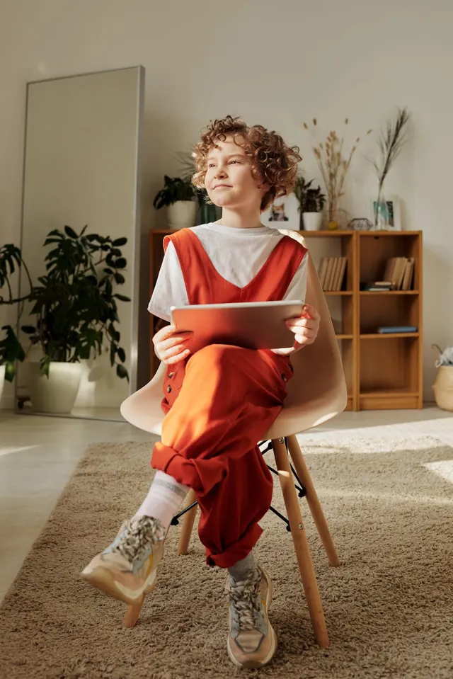 Child with tablet in sunlit room, photographic, minimal, warm