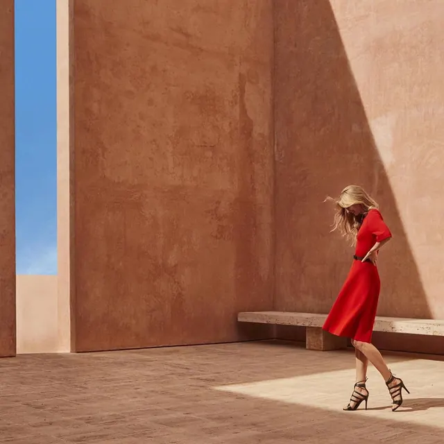 Red dress in terracotta architecture, photographic, minimal, warm