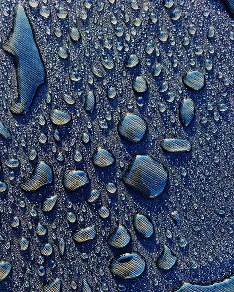 Water beads on navy technical fabric, minimal, photographic, cool