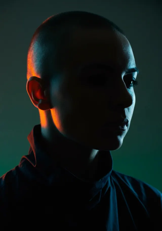 Teal-orange cinematic shaved-head portrait, photographic, dark-mode, dark
