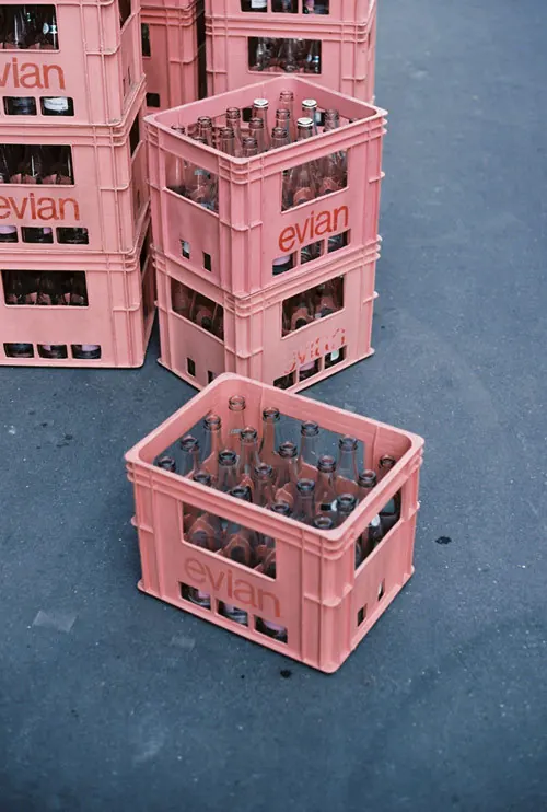 Pink evian bottle crates on asphalt, photographic, minimal, pastel