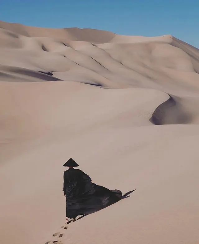Lone figure on orange-blue desert dunes, photographic, minimal, muted