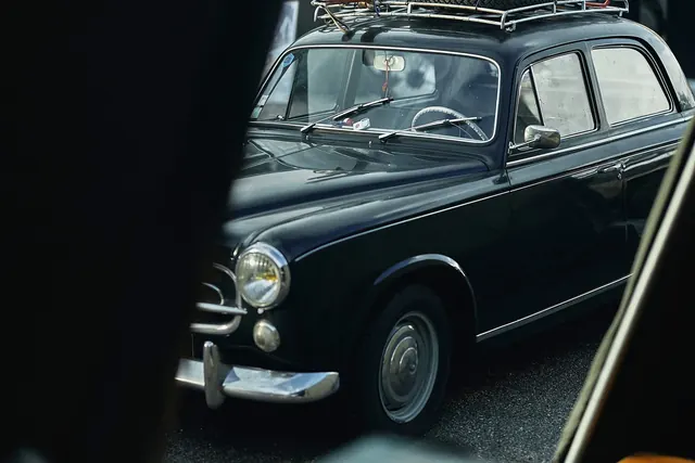 Vintage sedan through foreground blur, photographic, retro, muted