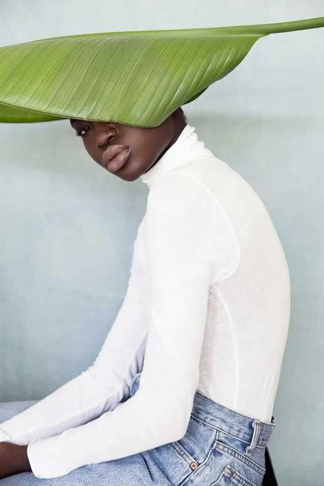 Fashion portrait with oversized green leaf, minimal, photographic, light