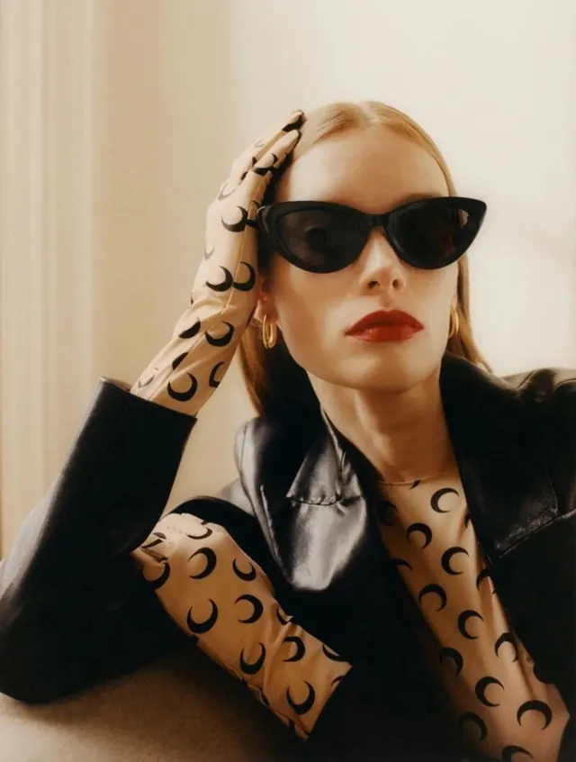 Fashion editorial with crescent moon blouse and cat-eye sunglasses, minimal, photographic, warm