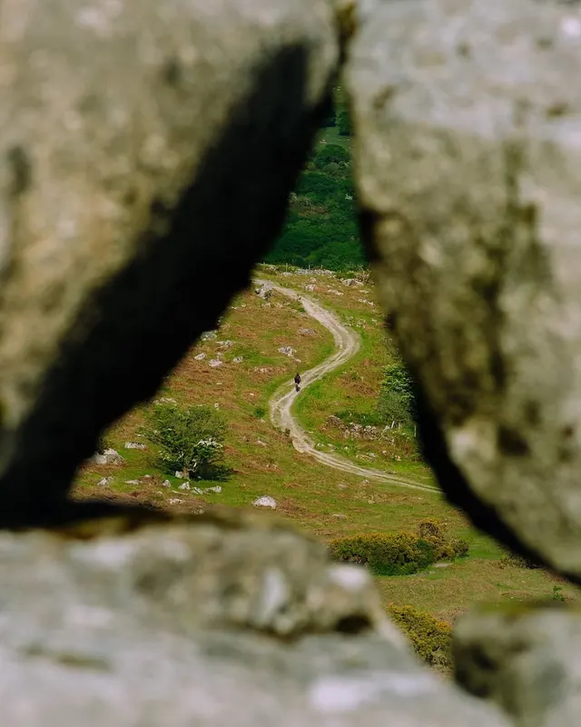 Winding path viewed through stone window, photographic, organic, earthy
