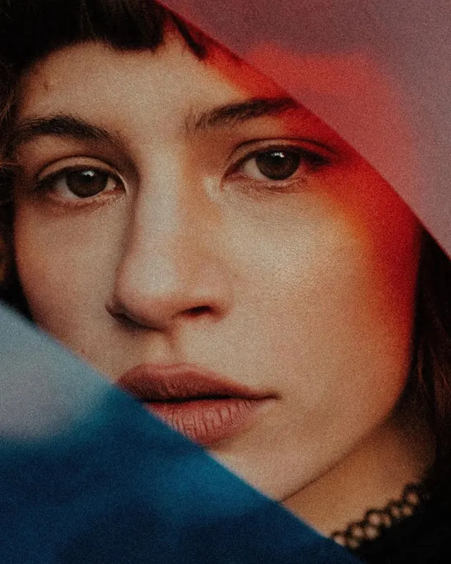 Close-up portrait with red lighting and sheer fabrics, photographic, dark