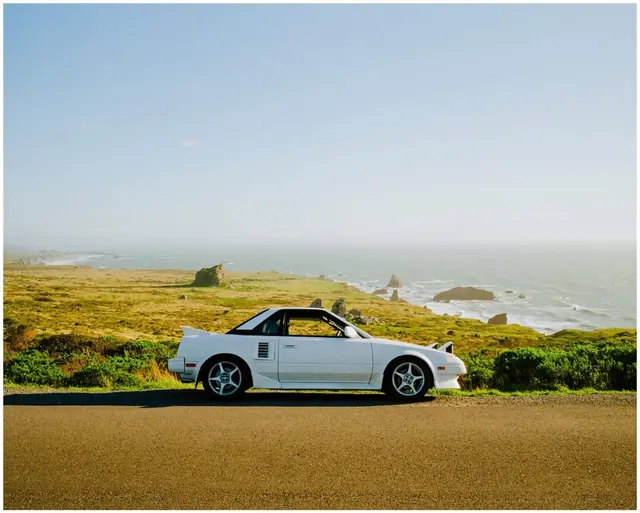 White Vintage Car on Coastal Grassland