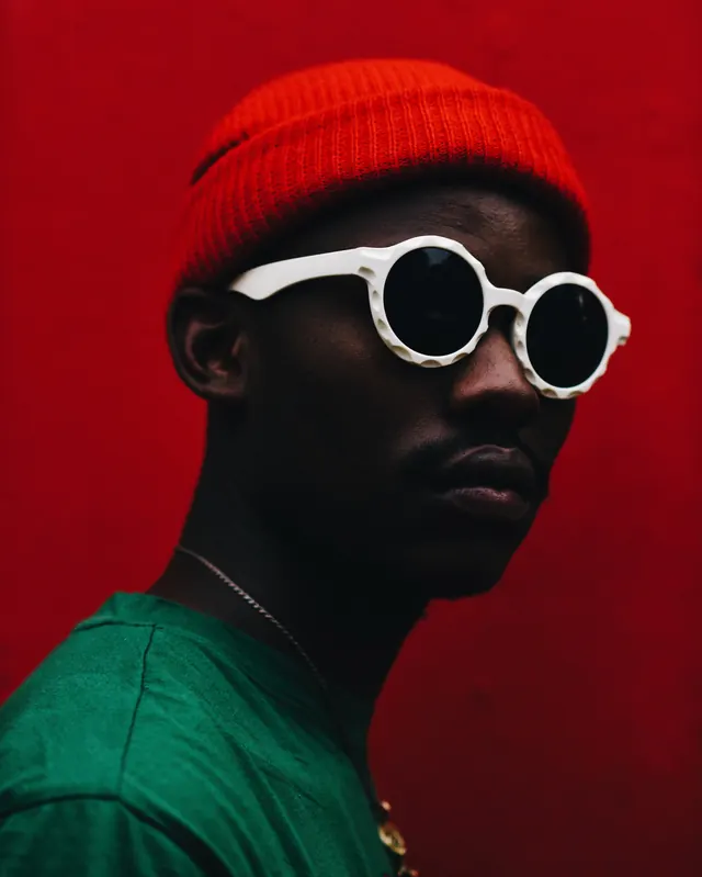Portrait with white round sunglasses and red beanie, photographic, minimalist, vibrant