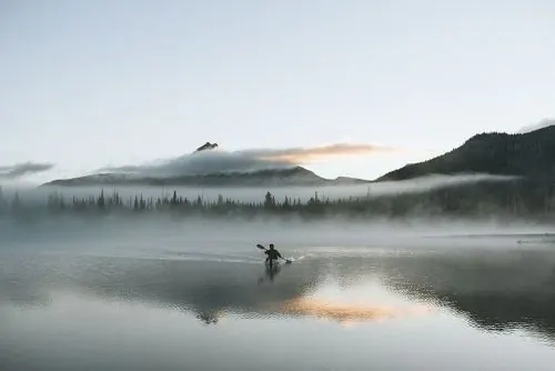 Misty lake landscape with kayaker, minimal, photographic, cool