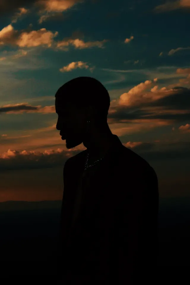 Silhouette profile against dramatic sunset sky, photographic, minimalist, dark