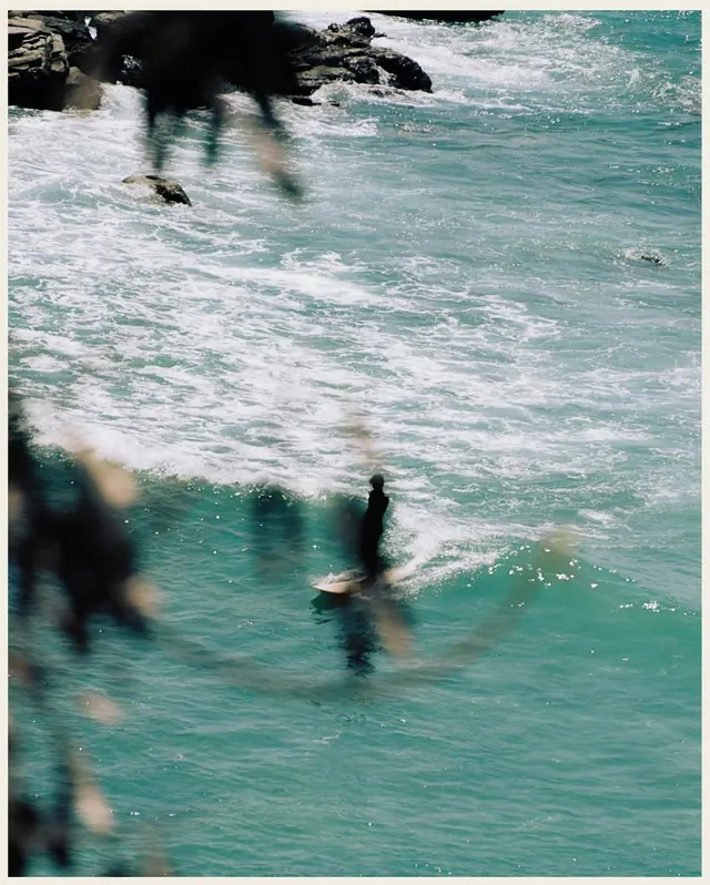 Motion-blurred surfer entering turquoise water, photographic, organic, cool