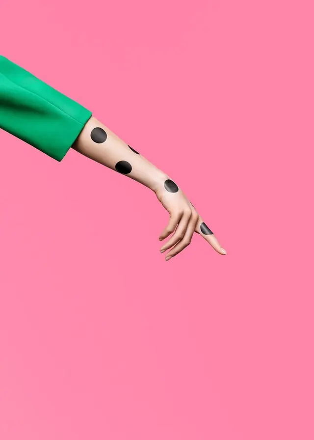 Arm with polka dots against vibrant pink background, playful, pop-art, vibrant