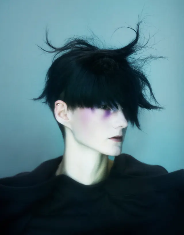 Portrait with flowing black hair and teal background, photographic, editorial, cool
