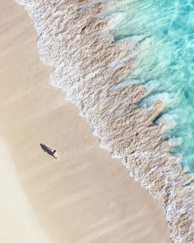 Surfer in turquoise ocean waves—aerial perspective, photographic, organic, cool