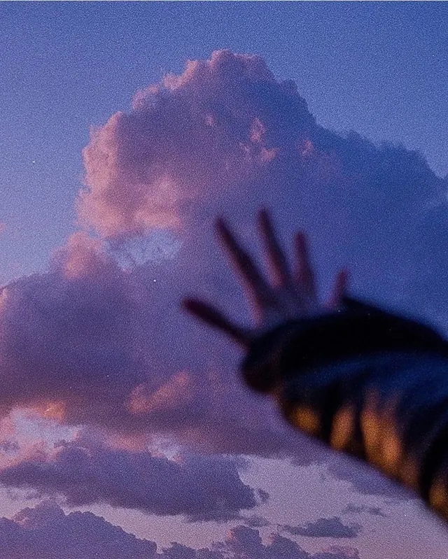 Hand silhouette against sunset clouds, photographic, gradient-heavy, pastel
