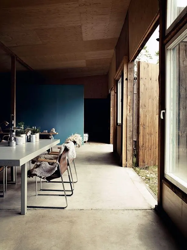 Industrial concrete dining space with teal feature wall, minimal, brutalist, cool
