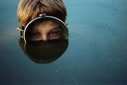 Child in diving helmet in water, photographic, monochrome, dark