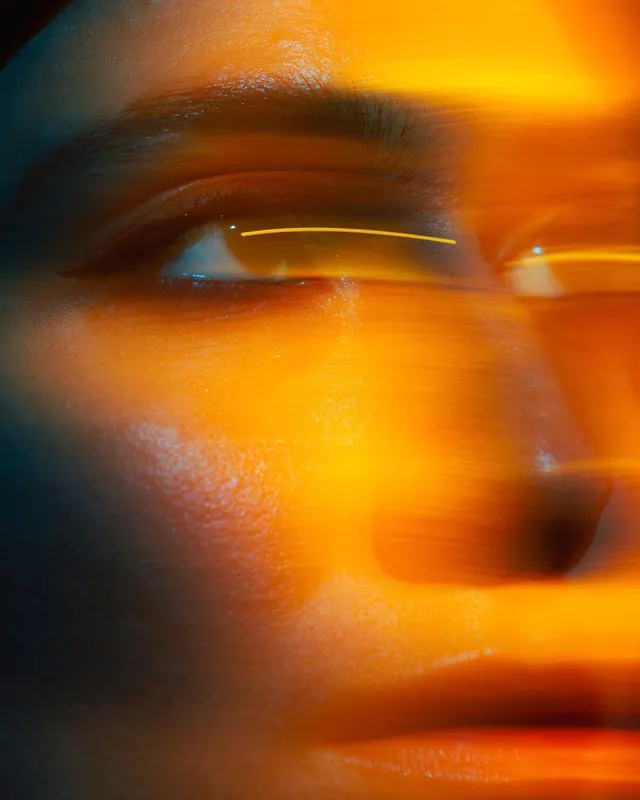 Cinematic orange-lit eye closeup, photographic, editorial, vibrant
