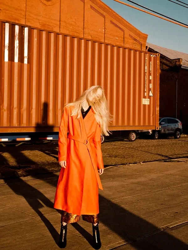Woman in Orange Coat in Industrial Setting