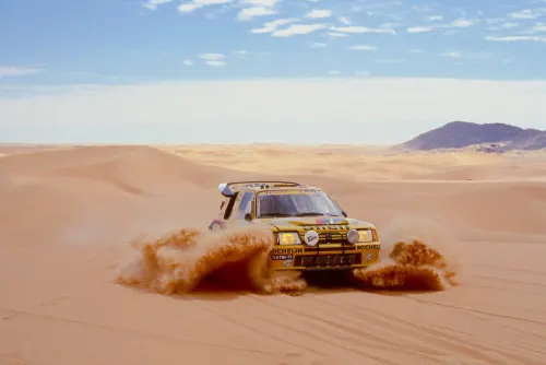 Yellow Peugeot rally car in desert dunes, photographic, warm