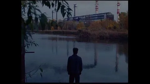 Man standing by a lake with industrial background