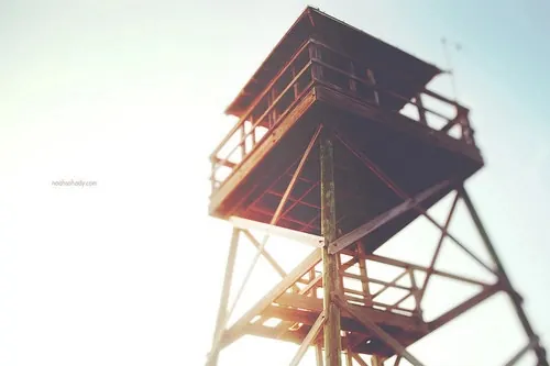 Wooden lifeguard tower against bright sky with sun flare, photographic, light