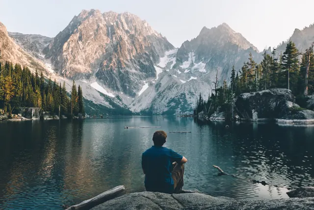 Man sitting by mountain lake