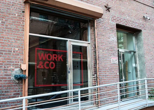 Brick storefront with red signage, photographic, corporate-clean, warm