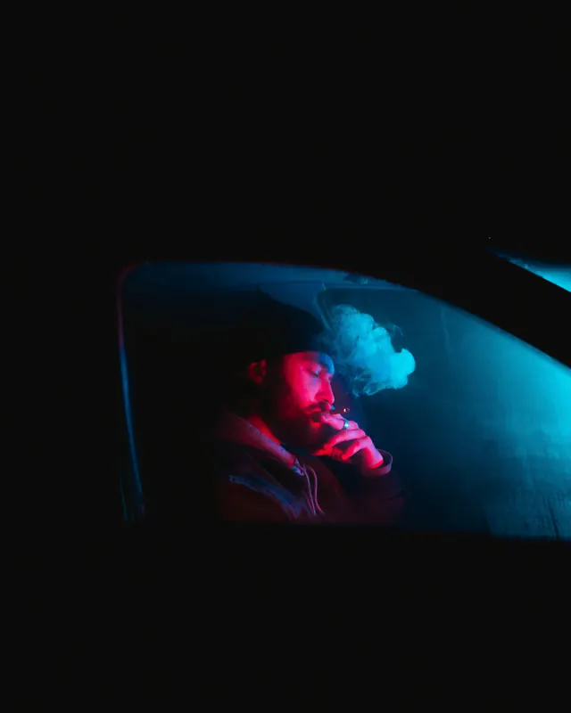 Neon-lit portrait inside dark vehicle, photographic, dark-mode, dark