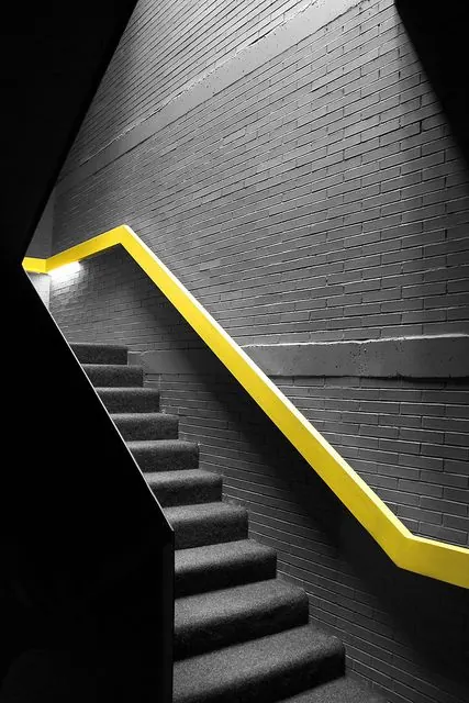 Stairwell with bright yellow handrail, minimalist, geometric, dark