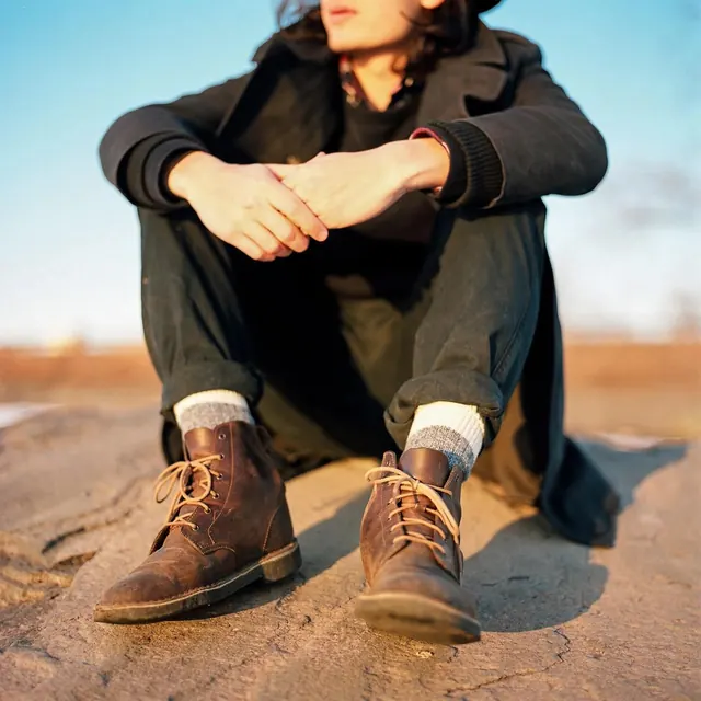 Person sitting on sand in natural light portrait, photographic, warm, warm