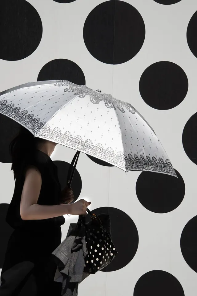 Silhouetted figure with umbrella against geometric circles, photographic, geometric, dark