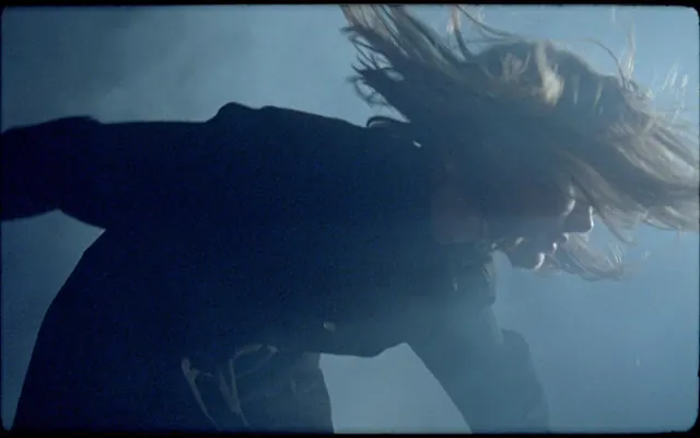 Figure in motion with flowing hair, photographic, dark-mode, cool