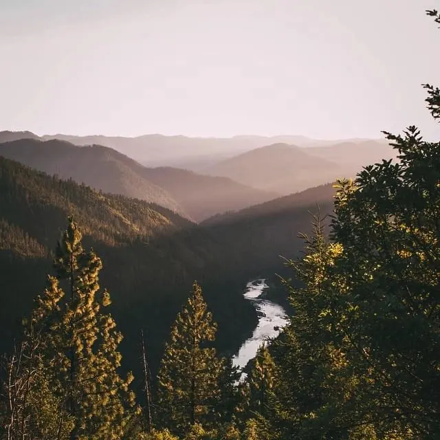 Mountain valley landscape with river at golden hour, photographic, organic, warm