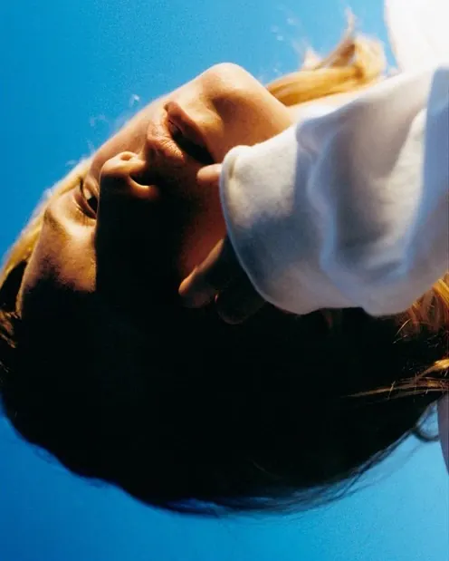 Portrait of person underwater against blue background, photographic, minimalist, cool